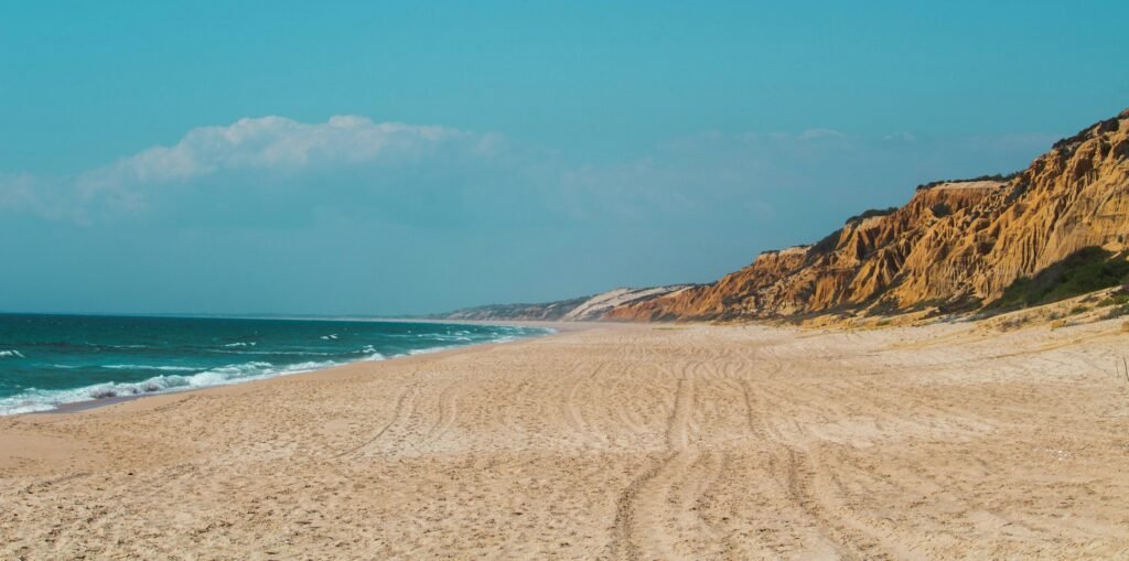 praia de areias douradas, mar em tons de azul e costas suaves na Costa Alentejana em Alentejo, Portugal