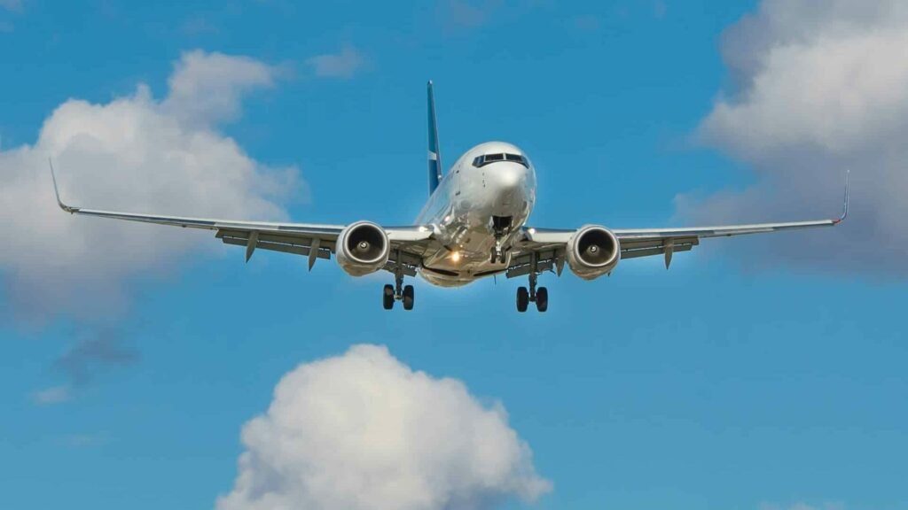 Avião voando em um céu com poucas núvens durante o dia. Foto de John McArthur via Unsplash