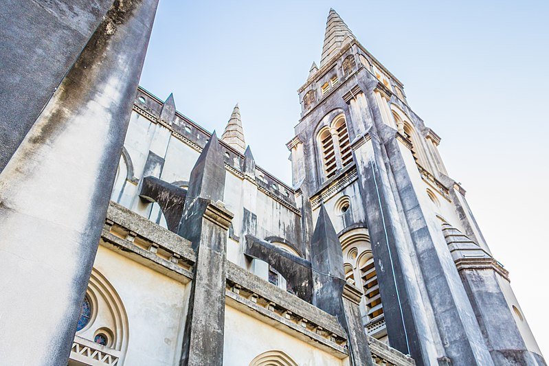 Foto da Catedral Metropolitana de Fortaleza, um dos pontos turísticos em Fortaleza, em um ângulo de baixo para cima, focando nas torres da construção. O céu está claro e sem nuvens.