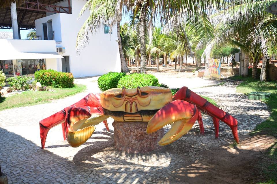 Entrada do Chico do Caranguejo em Fortaleza. Há uma escultura de caranguejo na entrada e atrás há várias palmeiras.