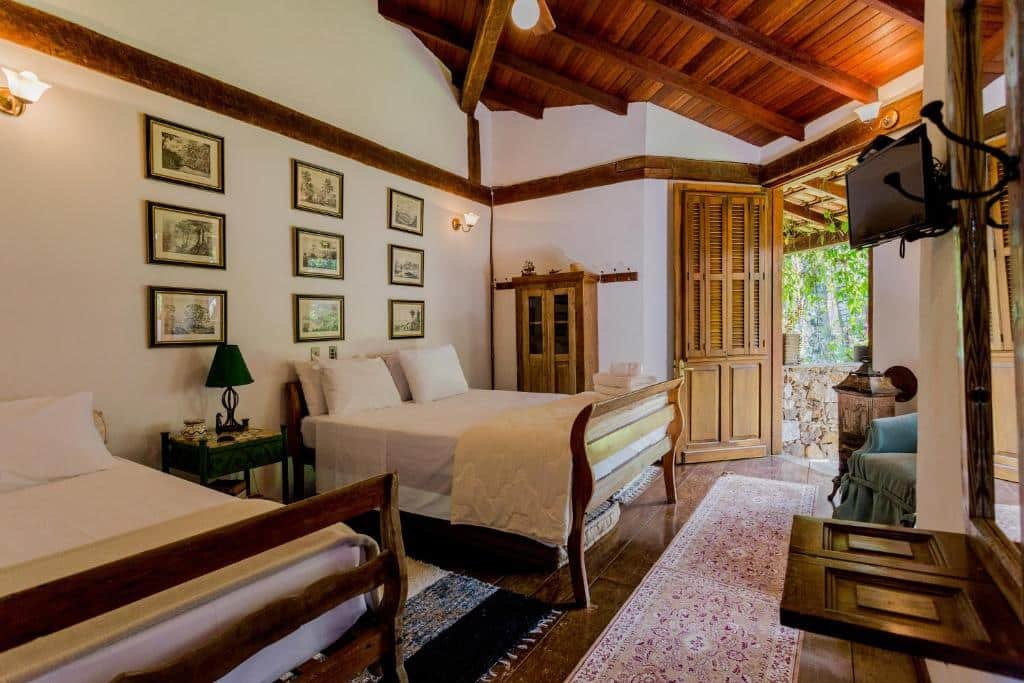 Quarto todo decorado, com fotos na parese, cama de casal, TV e armarinhos, da pousada em Ilhabela Feiticeira Guesthouse