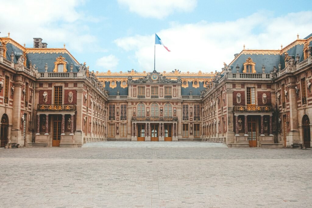 fachada imponente e detalhada em dourado e azul do Palácio de Versalhes, na França