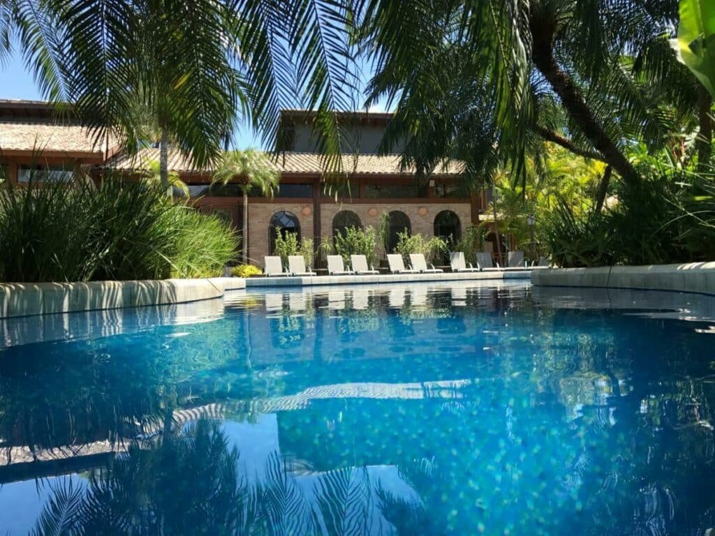 Piscina da Villa Bebek Hotel cercada por espreguiçadeiras e árvores.