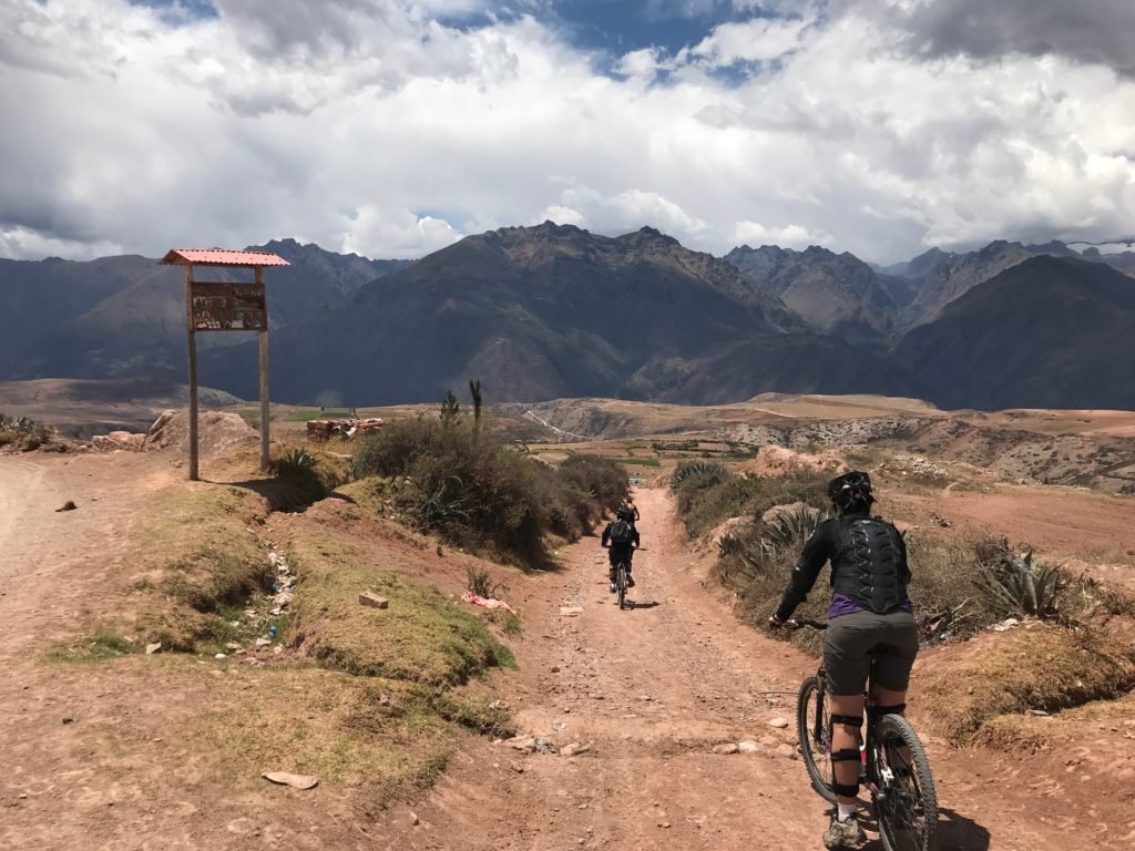 duas pessoas pedalando numa estrada de terra em direção ao parque arqueológico de moray, no vale sagrado dos incas