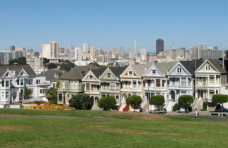 Casinhas em estilo vitoriano (Painted Ladies) em Alamo Square. Elas estão enfileiradas e todas tem cores neutras e parecidas. Foto para a lista de o que fazer em San Francisco.