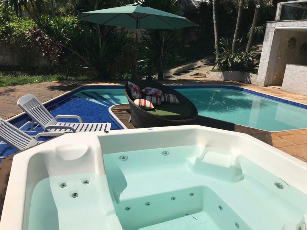 Hidro e piscina da pousada Albergo Alegria, em Macacos, com poltronas e espreguiçadeiras nos lados e um jardim ao lado
