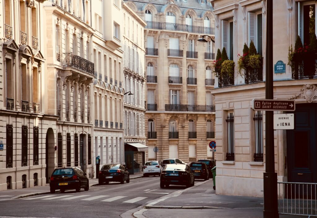 Uma rua tranquila em um bairro parisiense com carros estacionados, arquitetura clássica e uma placa de trânsito para Avenue d