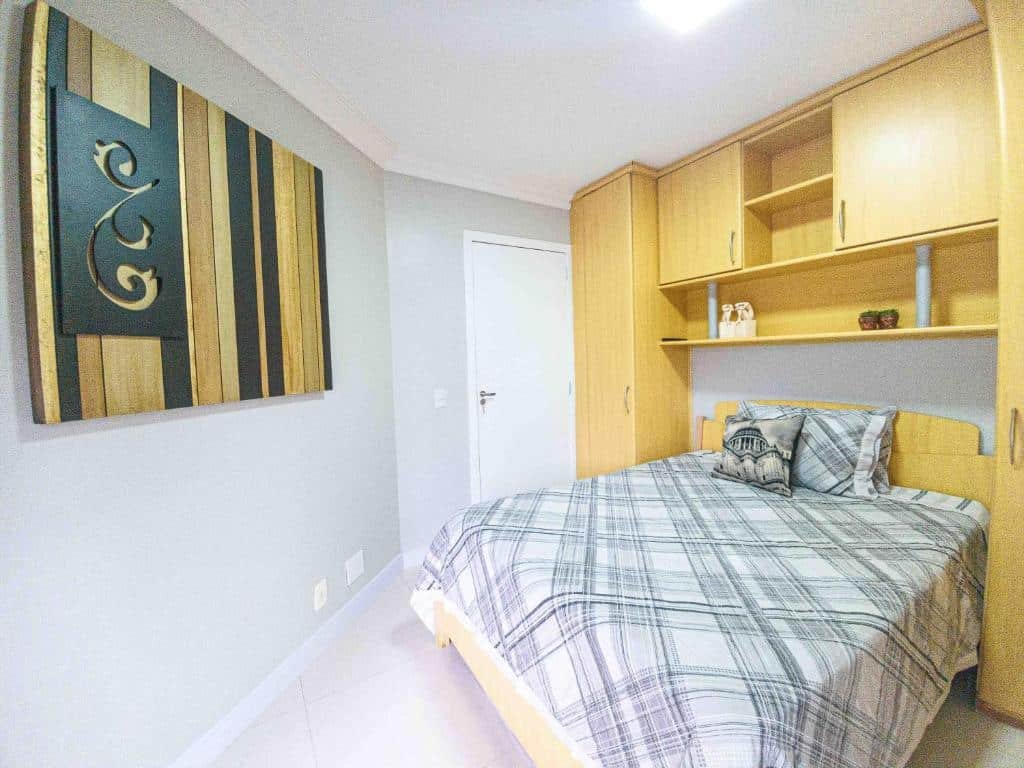 Quarto do Apartamento Pontal Norte. Do lado direito armários ao redor e uma cama de casal, no fundo a porta do quarto. o lado esquerdo um quadro na parede. Foto para ilustrar post sobre airbnb em Balneário Camboriú.