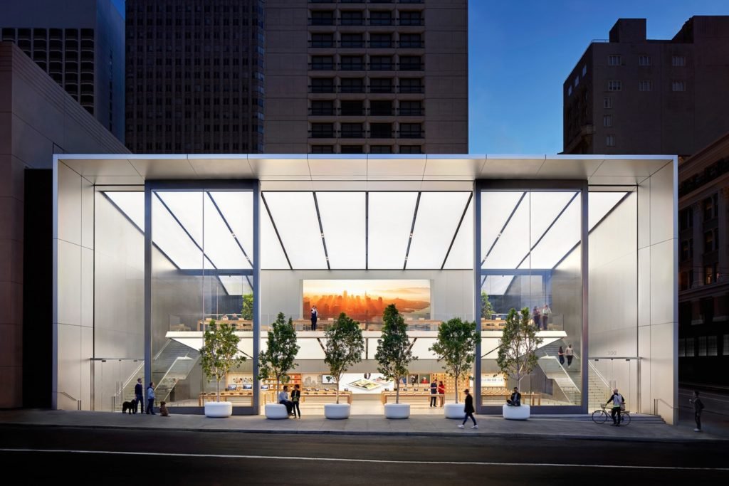 vista frontal da Apple Union Square, uma das lojas onde comprar em San Francisco. O espaço é todo quadrado e iluminado, com grandes paredes de vidro, podendo enxergar as escadarias dentro
