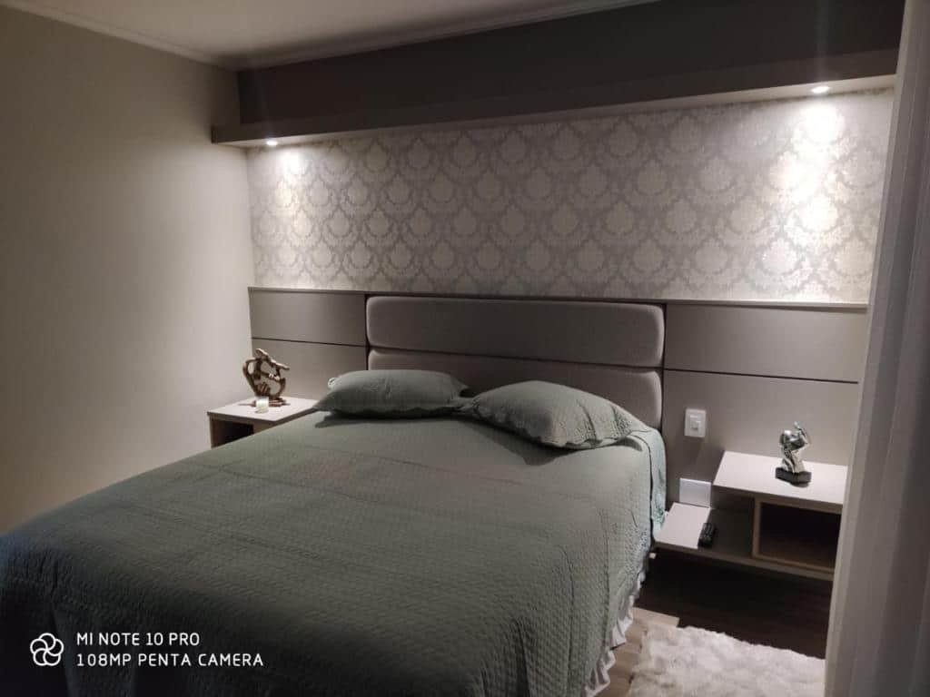 Quarto no Lindo apartamento no centro de Canela. A cama box de casal está no centro, atrás há uma cabeceira com tomada. Representa o post sobre airbnb em Canela.