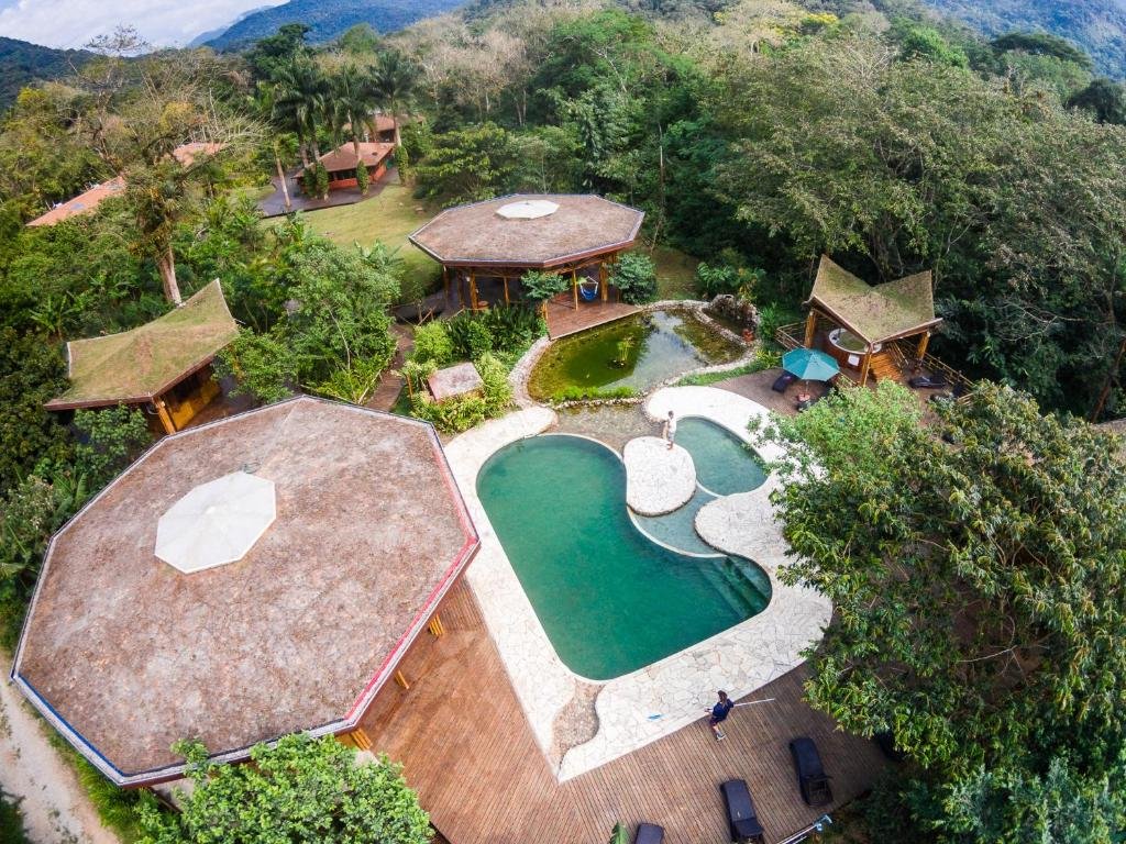 Área externa em Banana Bamboo Ecolodge, uma piscina, uma lago, muitos espaços verdes com varandas e cercado por vegetação, para representar airbnb em Ubatumirim.