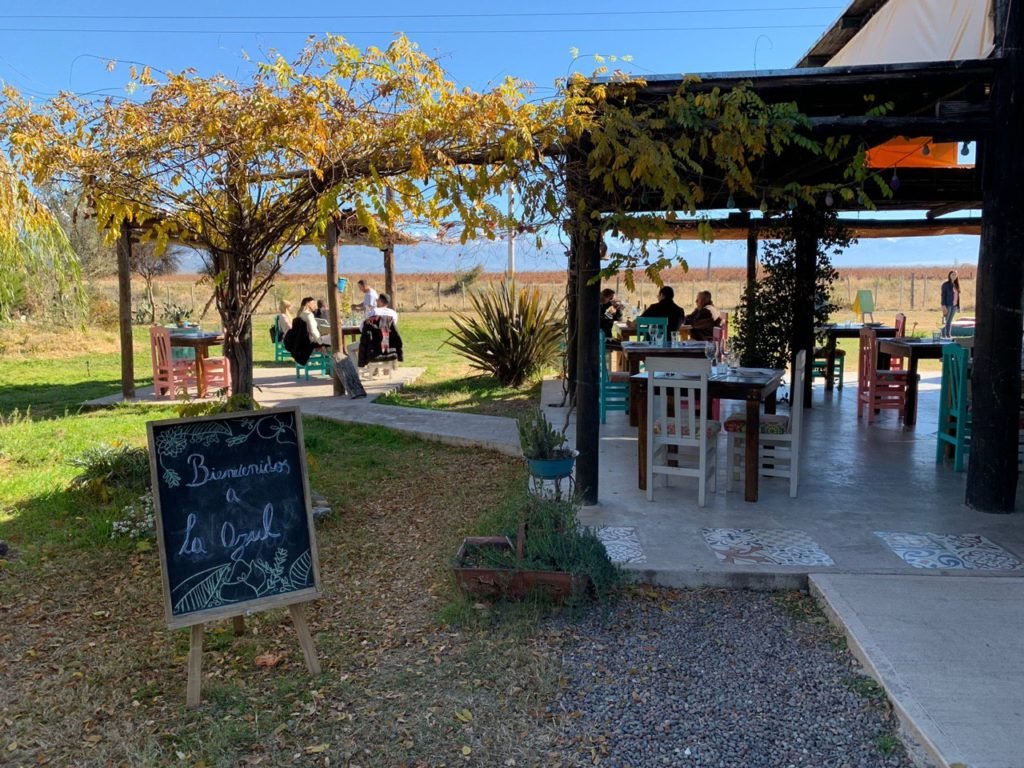 Na foto vemos a entrada do restaurante na vinícola La Azul. Há uma placa de lousa onde se lê "Bienvenidos a La Azul", algumas plantas, mesas e cadeiras. Foto: Bruno Tavares - Vinicola Mendoza