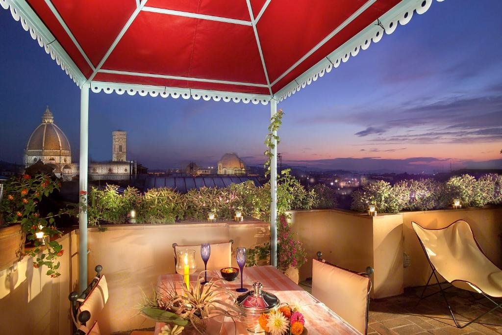 Varanda do Boutique B&B Antica Johlea, com mesa com vela, taças e flores em cima, e vista para uma noite na cidade de Florença