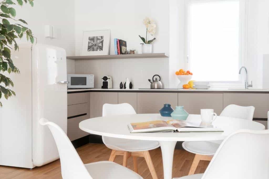 Cozinha do Brera Apartments in San Babila com uma janela com cortinas, uma geladeira, microondas, cafeteria, chaleira e itens de decoração, há também uma mesa redonda com quatro lugares, para representar onde ficar em Milão