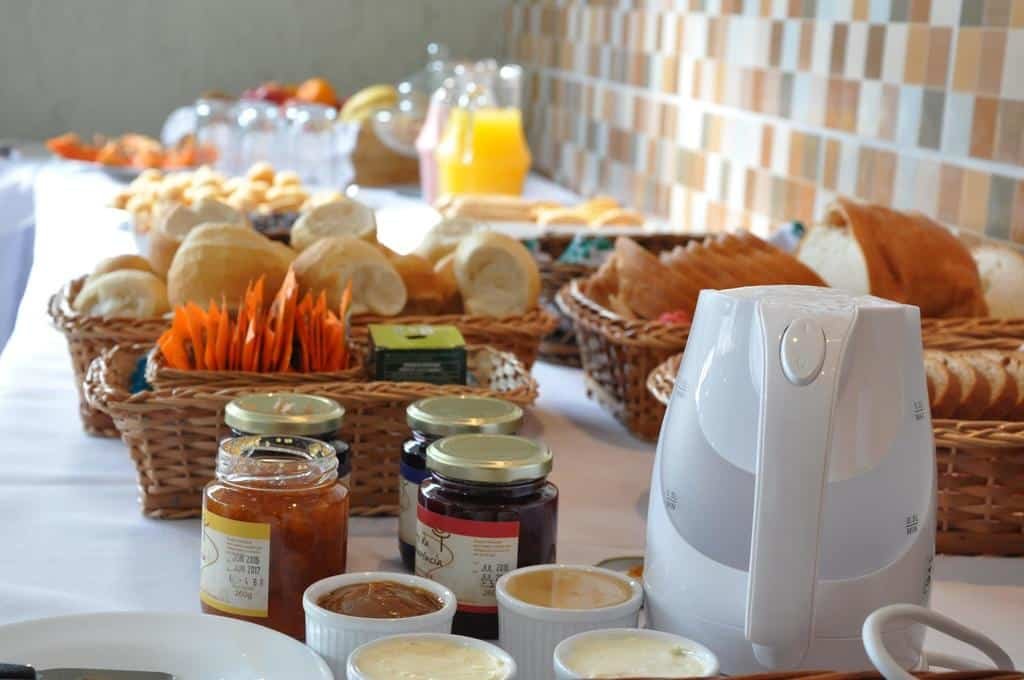 mesa com várias cestas repletas de pães, bolos, geléias, frutas e jarros de suco na Pousada Encanto dos Cânions em Cambará do Sul