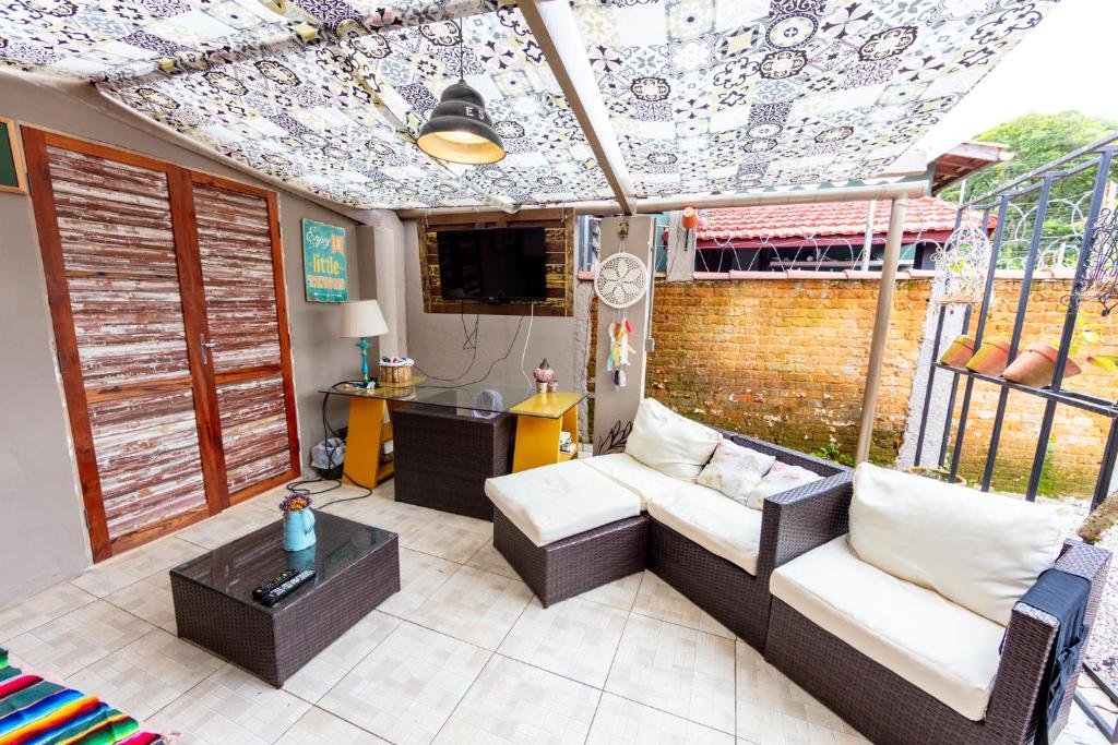 Área de uso comum na Casa Alma Zen, com sofá, mesa, TV e mesa de centro