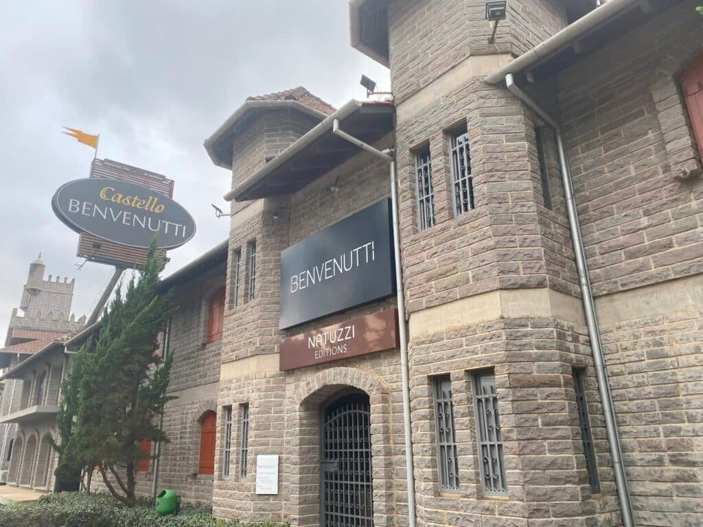 Fachada de pedras do Castello Benvenutti, com janelas estreitas e com grades, além de porta de entrada ampla e igualmente fechada com grade