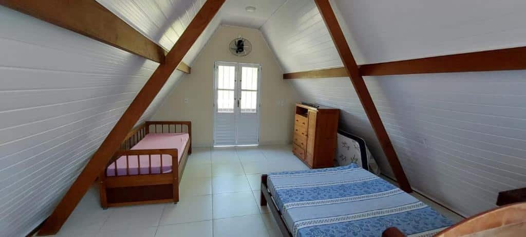 Quarto do Chale da Dalva. Uma cama de casal do lado direito, na frente uma cômoda e um colchão em pé. Do lado esquerdo uma cama de solteiro e no meio uma porta. Foto para ilustrar post sobre airbnb em Ubatumirim.