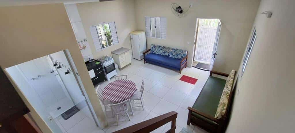 Cozinha do Chale da Dalva. Do lado esquerdo a porta do banheiro, no meio uma mesa, do lado direito e no fundo um sofá cama, no canto esquerdo a cozinha.