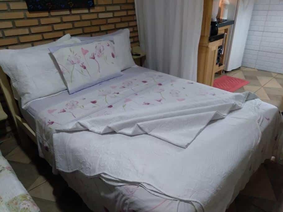 Quarto do chalé recanto Monte fuji. Uma cama de casal do lado esquerdo, no fundo uma minicozinha. Foto para ilustrar post sobre airbnb em Ubatumirim.