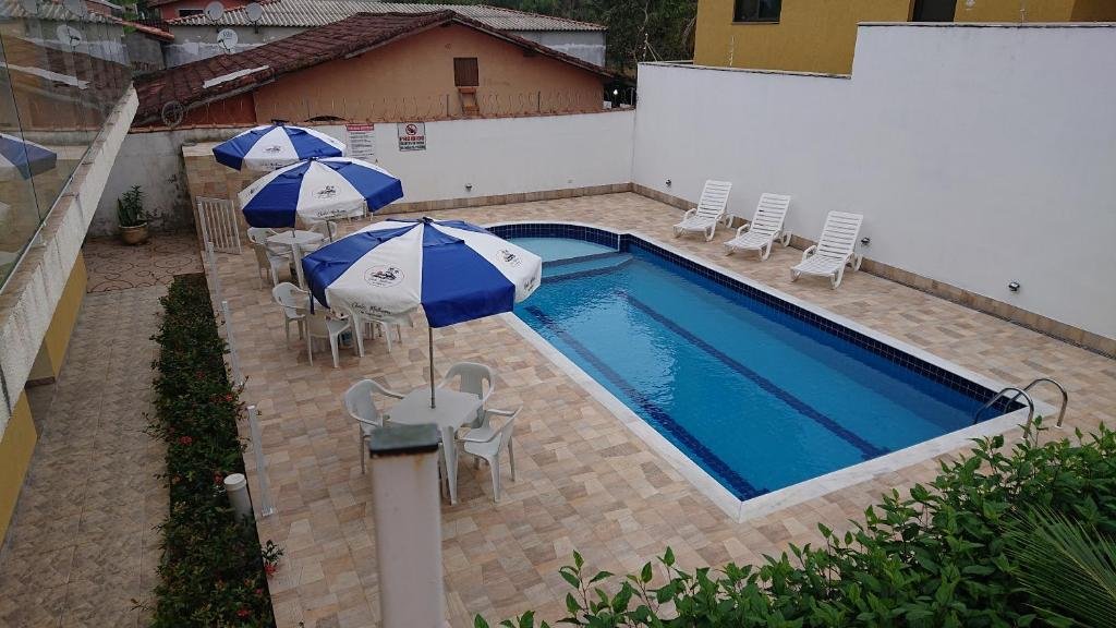 Piscina ao ar livre nos Chalés Mallumar, com espreguiçadeiras e cadeiras e mesas com guarda-sol