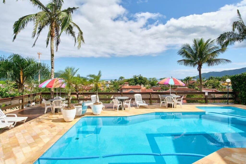 Piscina do Chalés Mirante da Lagoinha com um deck que dá vista para árvores, montanhas e a praia mais ao fundo
