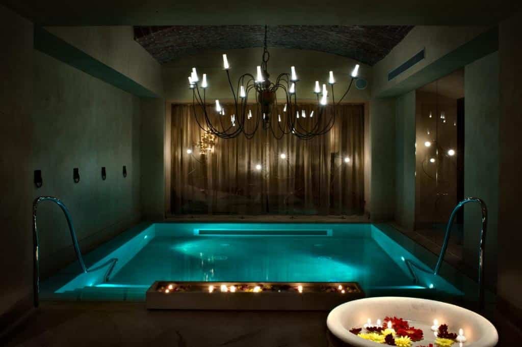 Piscina coberta do Château Monfort - Relais & Châteaux com um lustre no teto, um ambiente mais escuro e intimista