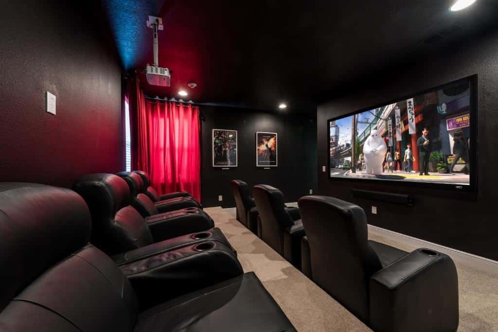 mini sala de cinema no Fabulous Home Near Disney with Private Pool, Movie Room, Themed Rooms & Resort Amenities, um das opções de onde ficar em Orlando, com poltronas confortáveis de couro preto com porta copos e um projetor que reflete na TV