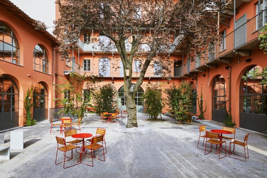 Terraço do Combo Milano com uma árvore no centro e outras pequenas árvores, há mesinhas e cadeiras pelo espaço