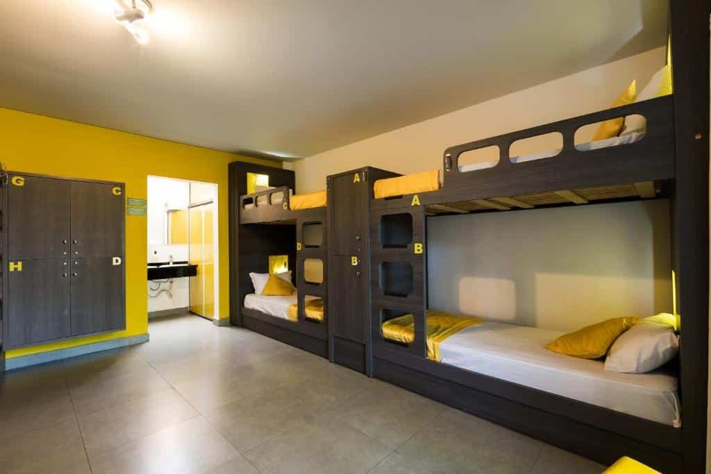 Quarto do Concept Design Hostel & Suites que mostra quatro beliches separadas por um armário de dois espaços. No quarto do lado esquerdo tem mais armários e do lado um espaço que dá acesso ao banheiro. Imagem ilustrando post Resorts em Foz do Iguaçu.
