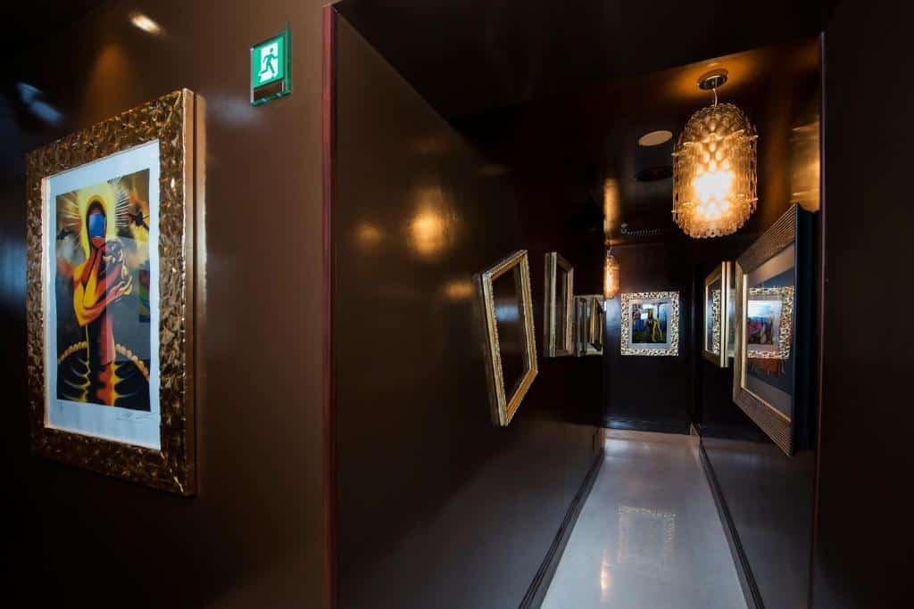 corredor todo preto e com lustres no Torre Argentina Relais - Residenze di Charme com obras de arte de molduras douradas