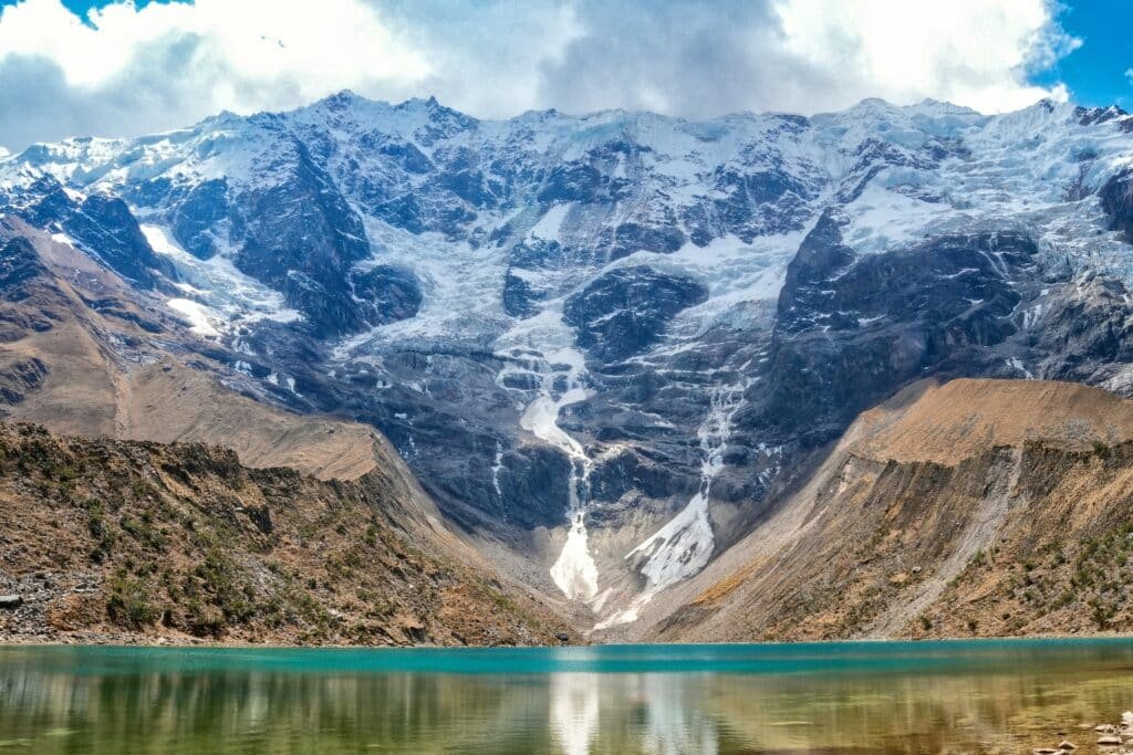 lago de água congelado das montanhas de Humantay, no Peru. Ao fundo é possível ver a cordilheira dos andes peruanos com suas montanhas congeladas, descendo gelo até o lago.