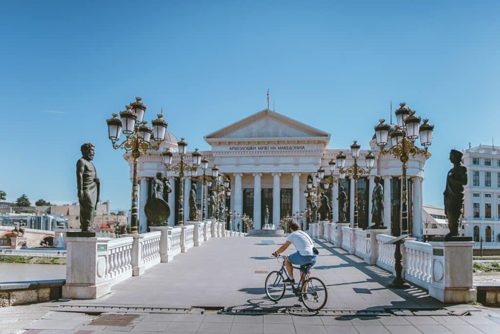 Pessoa andando de bicicleta em uma ponte tradicional da Escópia, capital da Macedônia
