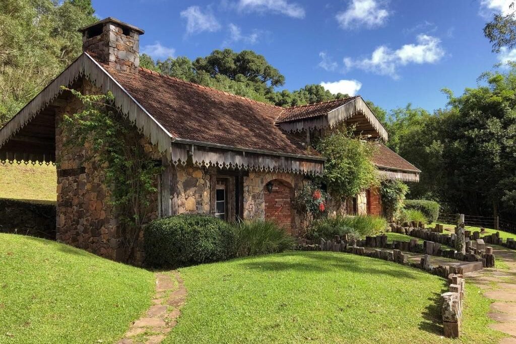 Uma foto do chalé da Estalagem La Hacienda. Sua estrutura é de pedra e está imerso à natureza.