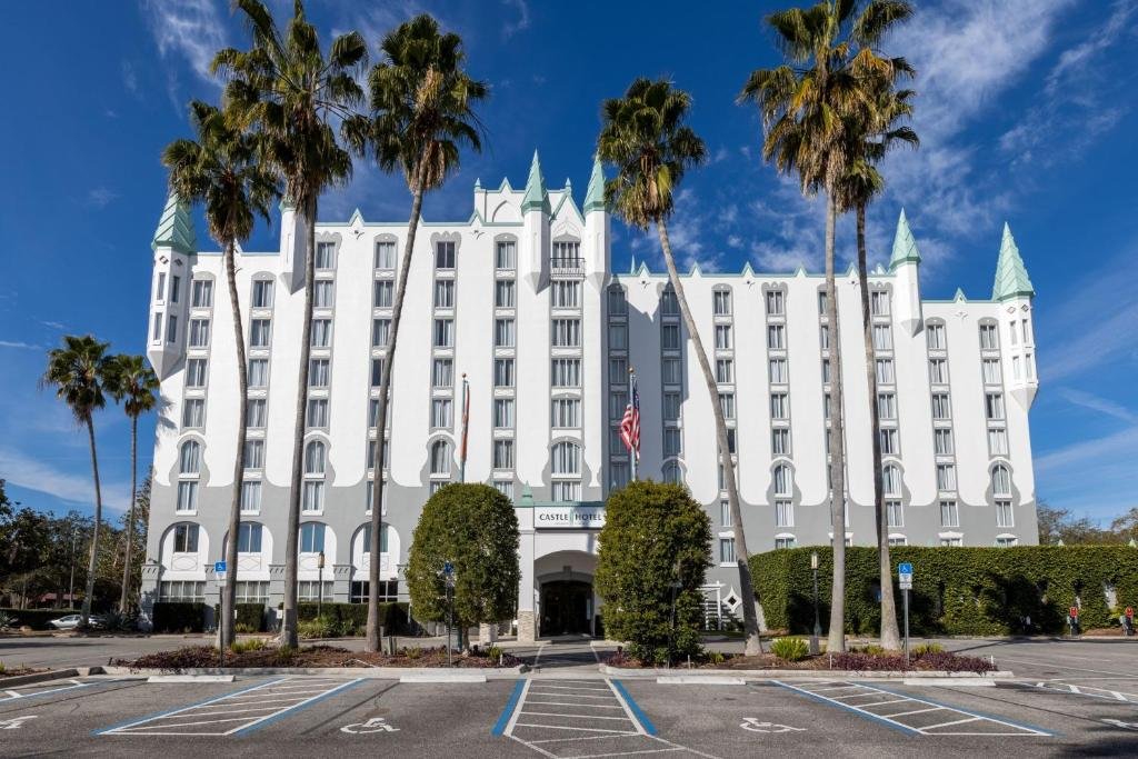 fachada do Castle Hotel, Autograph Collection by Marriott que, de fato, parece um castelo com paredes brancas e detalhes em azul com palmeiras na frente do Castle Hotel, Autograph Collection by Marriott, uma das opções de onde ficar em Orlando