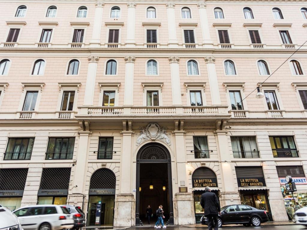 fachada do Queen Palace Suites em tons bege e trabalhada, com várias janelinhas que dão para a rua