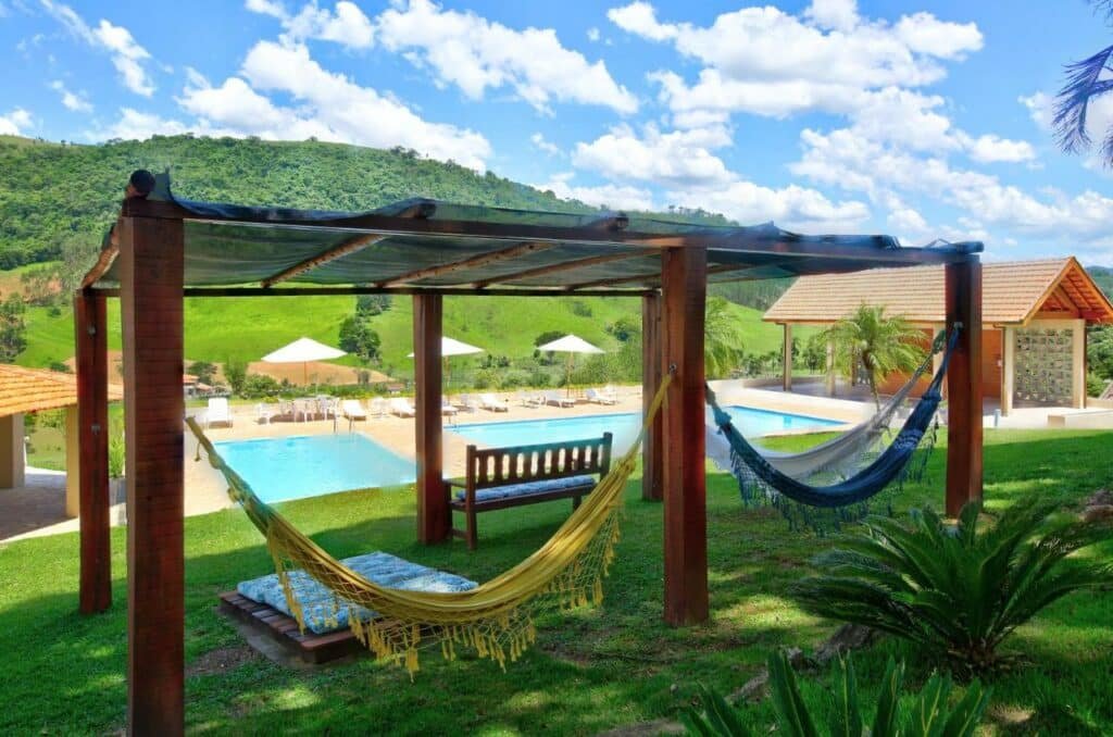 Região da piscina e gramado do Filimahalo Hotel com bangalôs com redes e vista para as montanhas, para representar hotéis em Serra Negra
