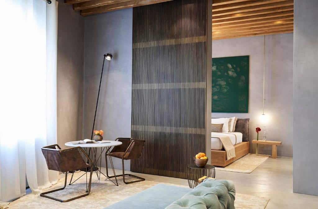 Interior do Fornace Suite, um aluguel de temporada em Florença, com uma sala de estar com mesa redonda e duas cadeiras, um sofá, além do quarto com cama de casal e mesa baixa de madeira com um vaso de flor em cima