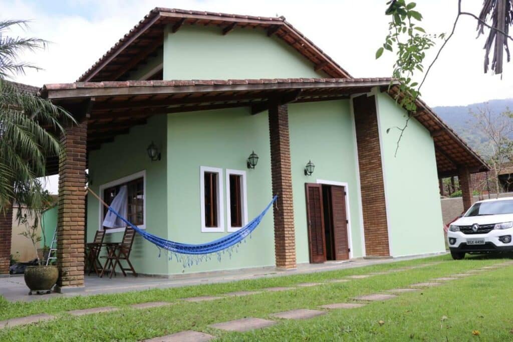 Frente do Aconchegante Casa de Temporada com grama a frente e ao fundo a casa.