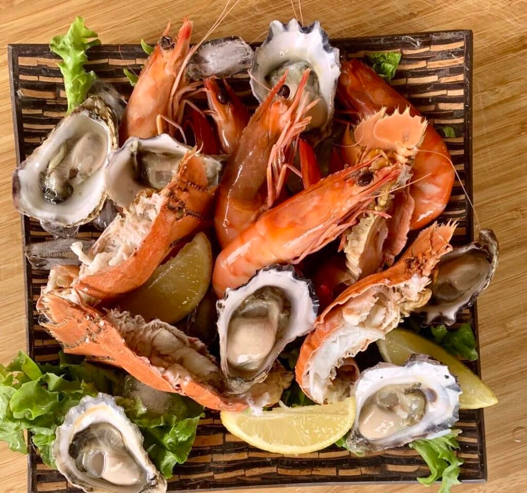 Um prato quadrado com camarões, ostras, pernas de caranguejo, fatias de limão e alface sobre uma superfície de madeira no The Gutter Bar em Moreton Island