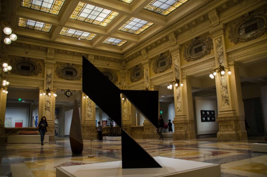 Uma grande escultura geométrica é exibida na Gallerie d’Italia. O museu é ornamentado com piso de mármore e teto de vitral.