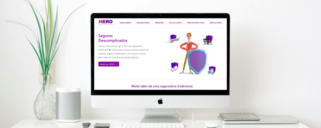 Um computador sob uma mesa com o site da Hero Seguros aberto na tela
