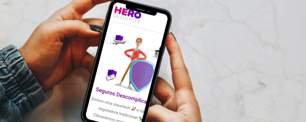 Uma mulher usando um celular sob uma mesa branca, na tela está aberto o site da Hero Seguros