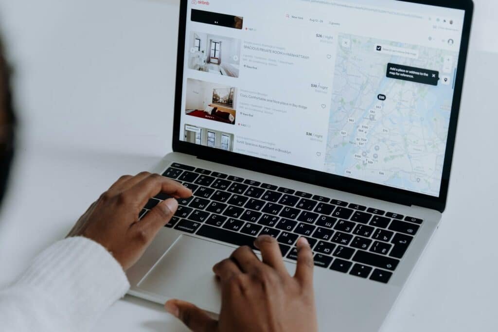 Mãos negras mexendo em um notebook com o site do Airbnb na tela