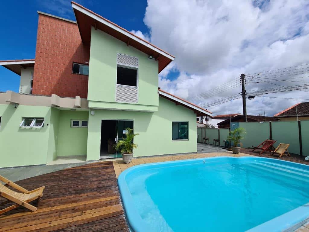 Piscina e edifício verde do Hostel Vila Itanhaém