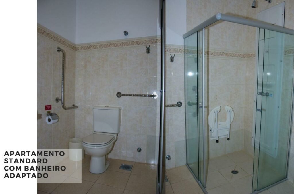 Banheiro com adaptações para PcD, com barras de apoio e assento auxiliar para banho dentro do boxe