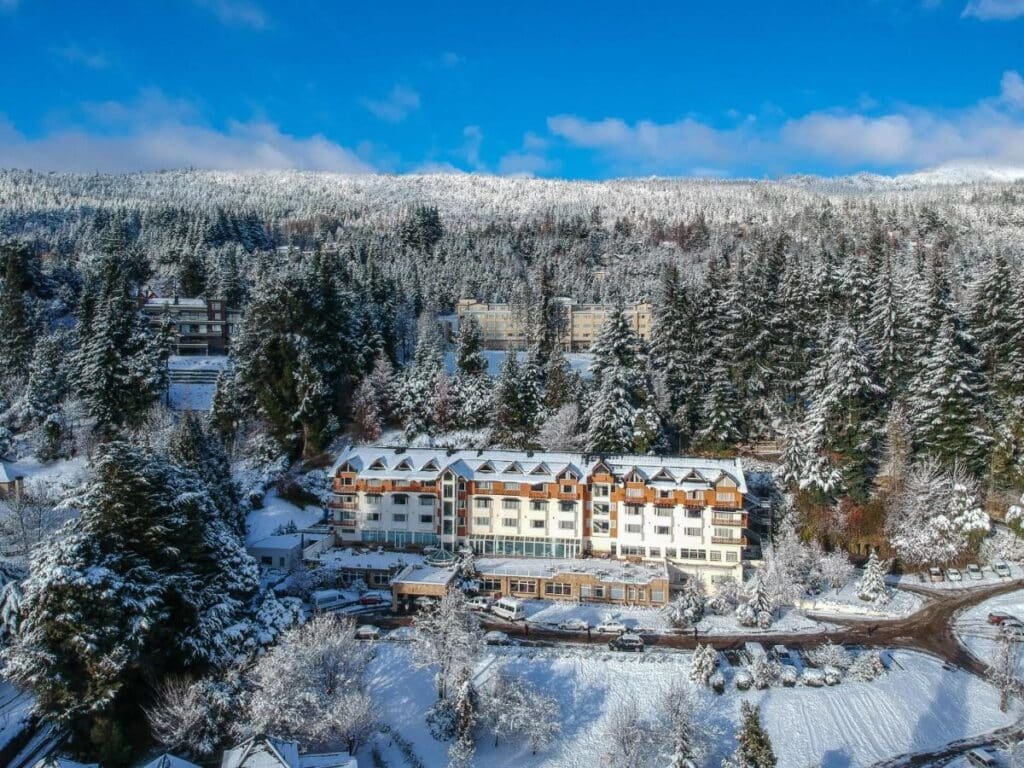 Vista aérea do Huinid Bustillo Hotel & Spa, com árvores e neve ao redor.