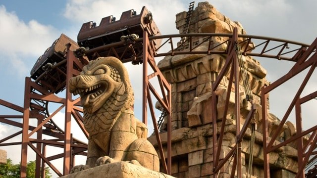 A montanha russa do Indiana Jones, com estatua de um leao e o looping ao fundo