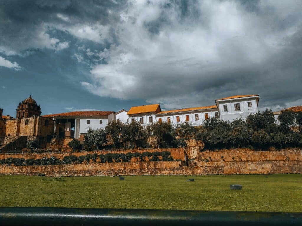 casa histórica ao lado de uma construção antiga e de tijolos, semelhante a uma catedral, em Cusco, para mostrar o templo do sol, também conhecido como Qoeikancha.