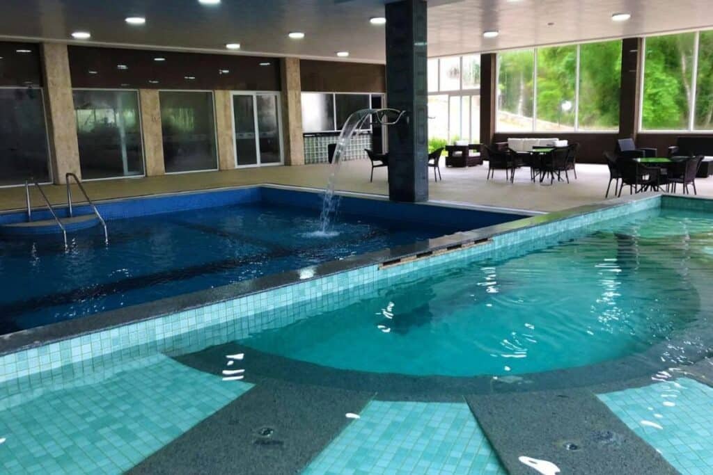 Área de piscina coberta no Itatiaia Resort & Eventos com duas piscinas conectadas, um espelho d